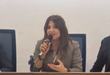 Calabria, Straface (ass. Welfare): “Oltre 18 milioni di euro per prevenzione e cura ludopatia” Woman in a grey blazer speaking into a handheld microphone at a panel discussion, with hands gesturing.