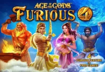 Slot online, mega vincita su Sunbet da 38.000 euro Game cover for 'Age of the Gods: Furious 4' with four mythic heroes—an armored warrior, archer, a pink-dressed goddess, and a muscular mythic fighter—standing in a blue/orange magical glow; title and subtitle visible.