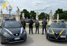 Padova: poker in una bisca clandestina. Sequestrati locali, 8 arresti e 24 denunce. Il video Five Guardia di Finanza officers stand between two patrol cars in a plaza with statues and trees in the background.