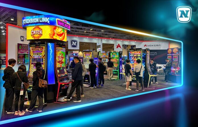 NOVOMATIC_G2E Asia People at a gaming expo exploring a row of bright arcade machines inside a neon-lit booth.