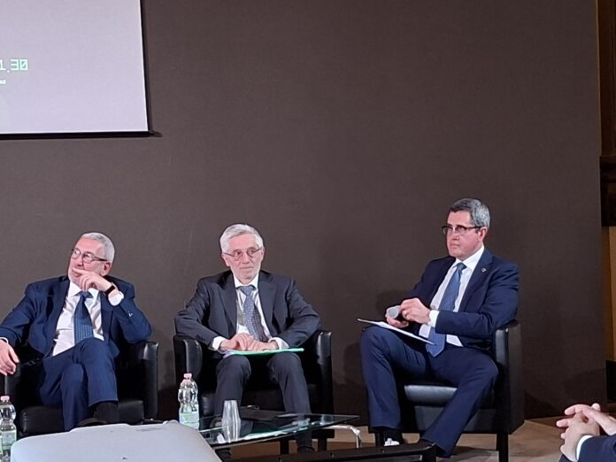 Sergio Silvestri Direttore della Scuola Italiana Antiriciclaggio e Compliance Three men in dark suits seated on a panel stage, engaged in a discussion at a conference.