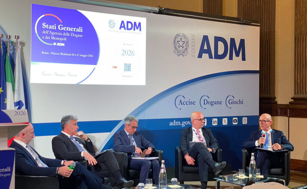 Panel of five men in suits seated on stage at an ADM event, with a large ADM banner and flags in the background.