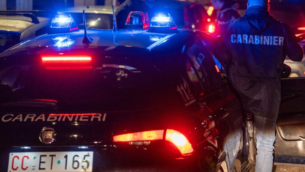Carabinieri Roma bisca clandestina | AGIMEG Italian Carabinieri patrol car with flashing blue lights at night, officer standing beside it