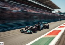 Scommesse antepost Formula 1, Antonelli sempre più leader: su Goldbet la sua vittoria è scesa a 1.20 Race car speeding down a track with blurred grandstands, foreground red-and-white curbs, and a sponsor logo at the corner (motion blur conveys speed).