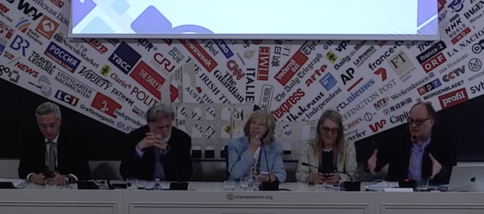Forum Famiglie Scommettere il Futuro Five panelists seated at a long white desk during a press conference, with a backdrop of various news logos and a projector screen above them.