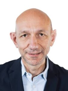 Marco Tasso Brightstar | AGIMEG Portrait of a bald man in a navy blazer and light blue shirt, smiling slightly, against a white background.