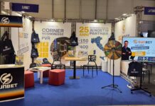 SunBet protagonista alla Fiera Nazionale dei Tabaccai Sunbet exhibition booth at a trade show with banners, tote bags, and a spinning prize wheel on a blue carpeted floor.